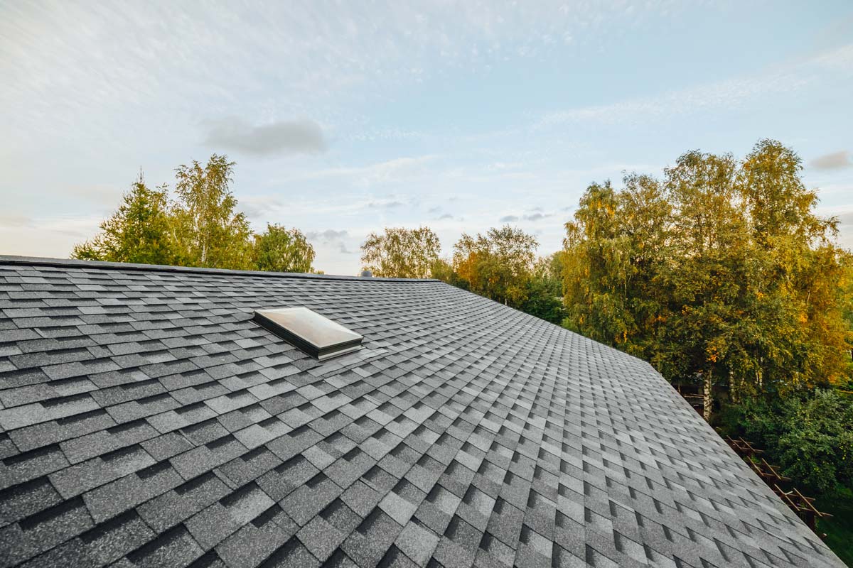 A man wearing a plaid shirt finishes working on a roof