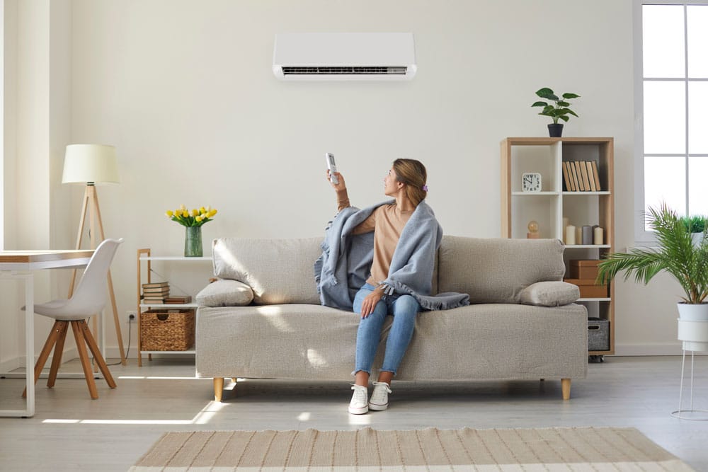 hvac-young-woman-turning-on-ac A modern home painted white with black trim. Modern, sleek solar panels cover the roof.