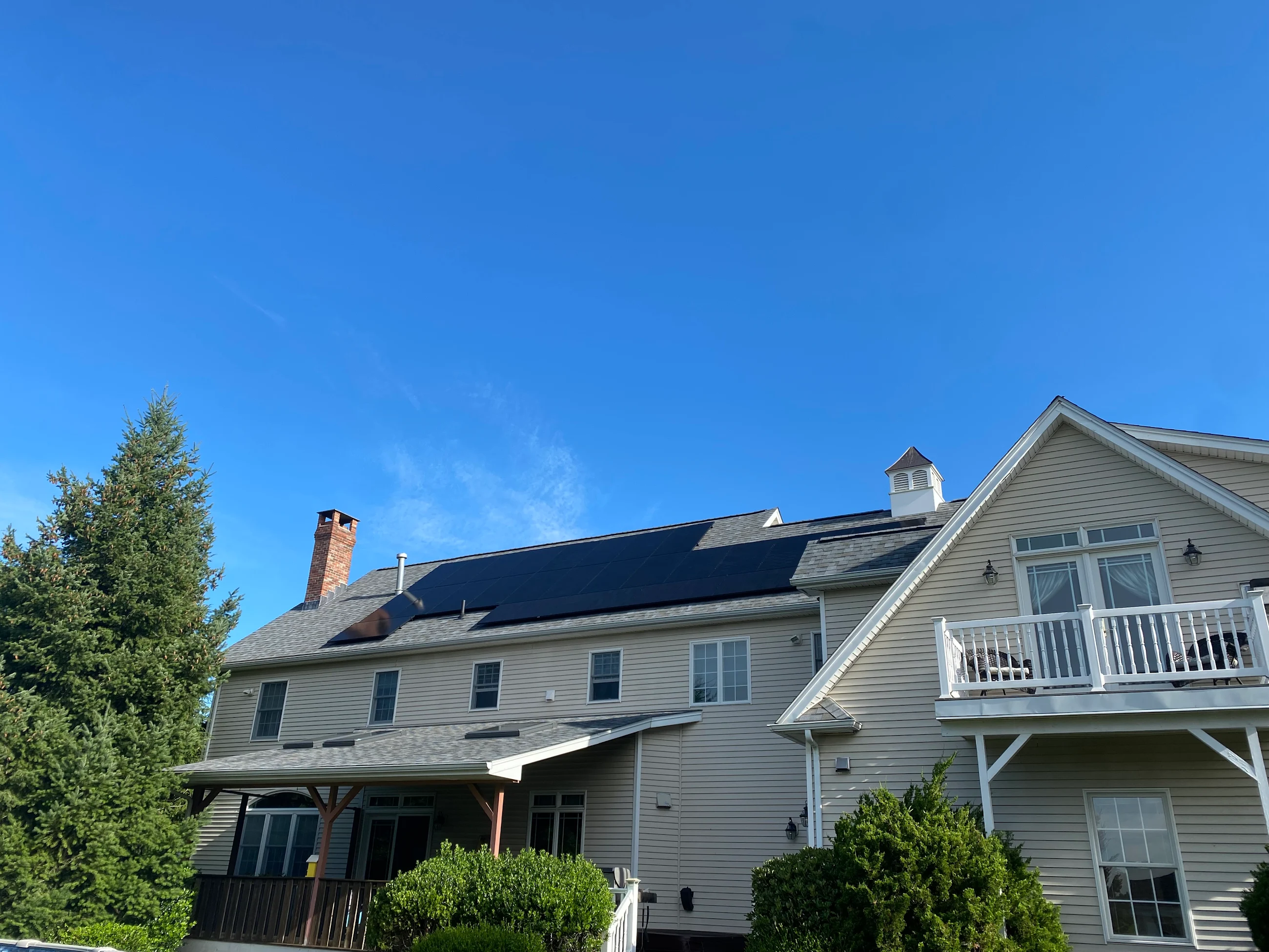 A modern A frame style house with sleek black solar panels on the room.